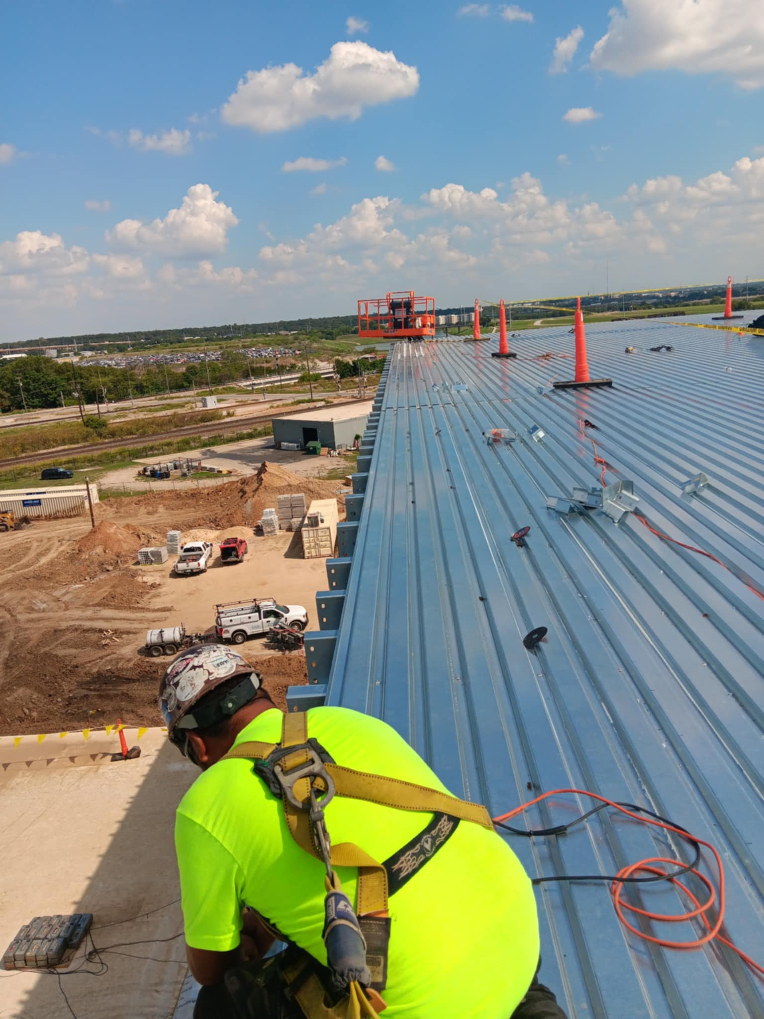MaloSteel crew member installing metal roof panels with safety harness